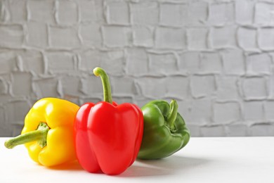 Photo of Ripe colorful bell peppers on white table. Space for text