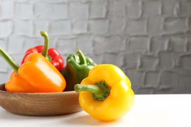 Photo of Ripe colorful bell peppers on white table. Space for text