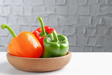 Photo of Ripe colorful bell peppers on white table. Space for text