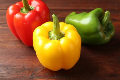 Photo of Ripe colorful bell peppers on wooden table, closeup