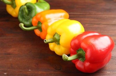 Photo of Ripe colorful bell peppers on wooden table, closeup