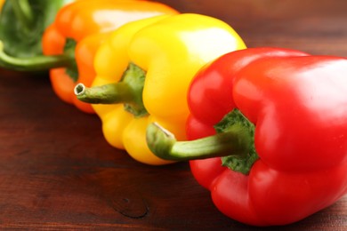 Photo of Ripe colorful bell peppers on wooden table, closeup