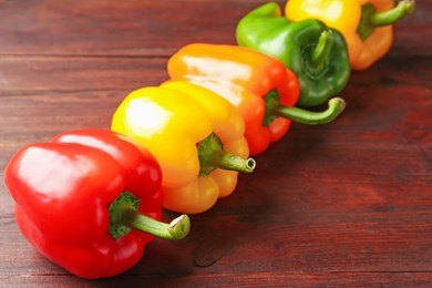 Photo of Ripe colorful bell peppers on wooden table, closeup
