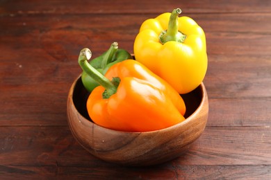 Photo of Ripe colorful bell peppers on wooden table, closeup