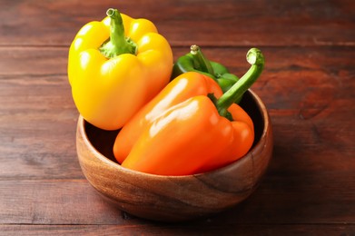 Photo of Ripe colorful bell peppers on wooden table, closeup