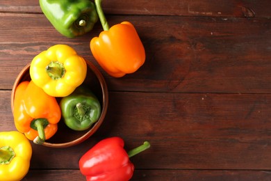 Photo of Ripe colorful bell peppers on wooden table, flat lay. Space for text