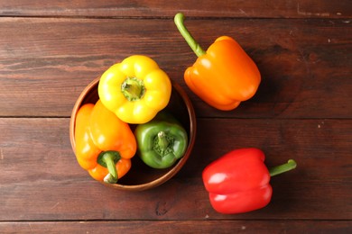 Photo of Ripe colorful bell peppers on wooden table, flat lay