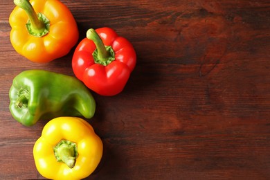 Photo of Ripe colorful bell peppers on wooden table, flat lay. Space for text