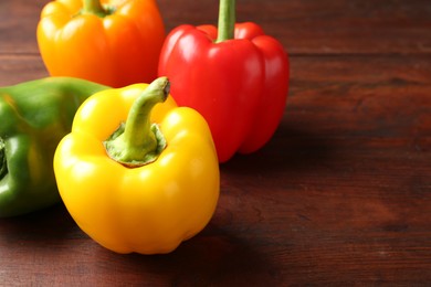 Photo of Ripe colorful bell peppers on wooden table, closeup