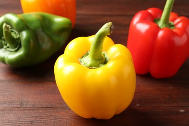 Photo of Ripe colorful bell peppers on wooden table, closeup