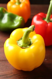 Photo of Ripe colorful bell peppers on wooden table, closeup