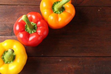 Photo of Ripe colorful bell peppers on wooden table, flat lay. Space for text