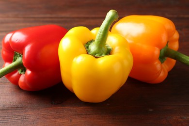 Photo of Ripe colorful bell peppers on wooden table, closeup