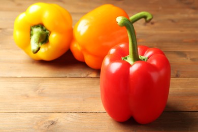 Photo of Ripe colorful bell peppers on wooden table, closeup