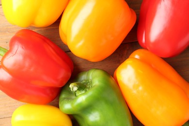 Photo of Ripe colorful bell peppers on wooden table, closeup