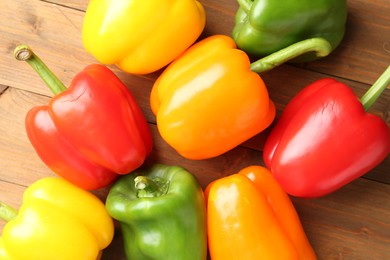 Photo of Ripe colorful bell peppers on wooden table, flat lay