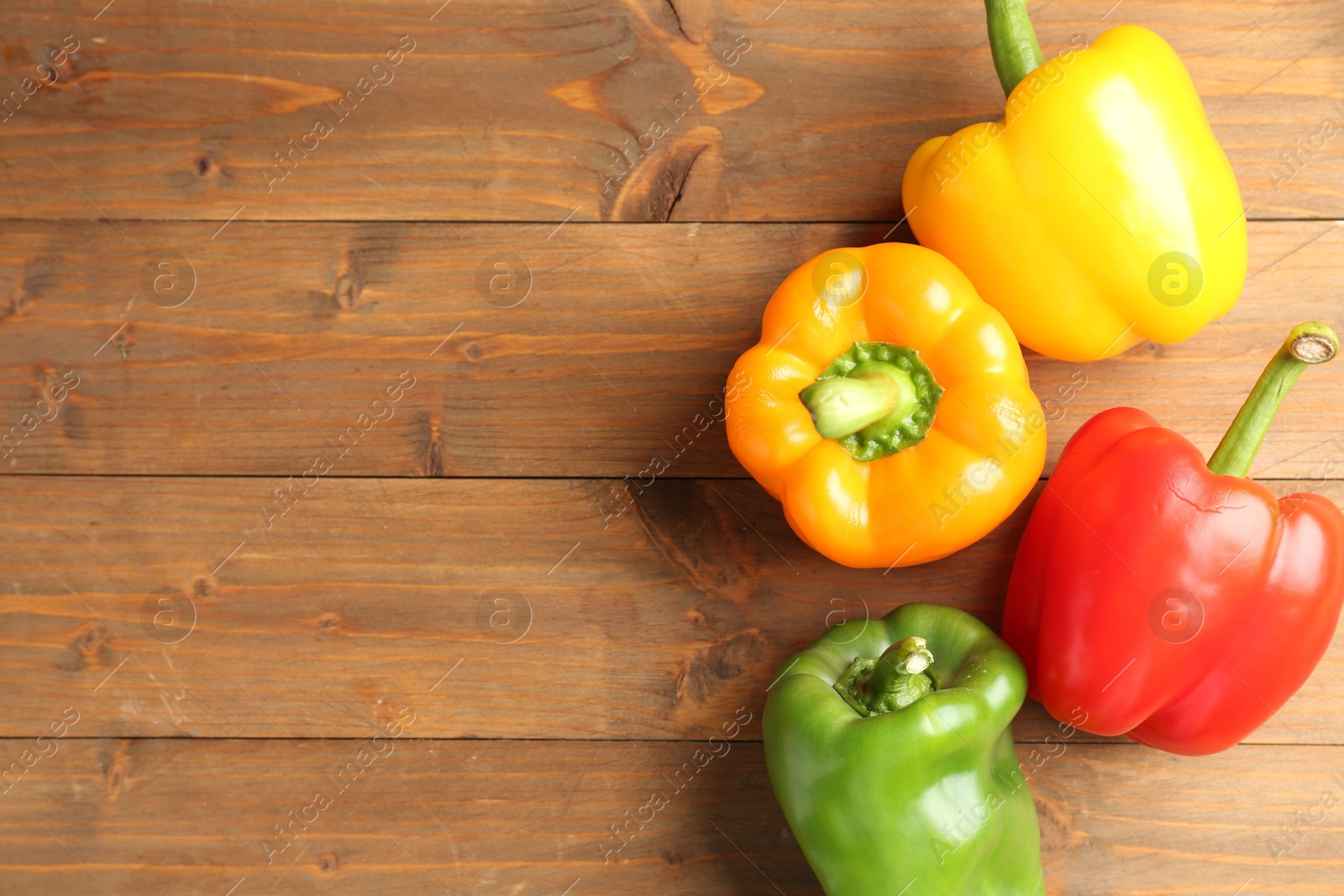 Ripe colorful bell peppers on wooden table, flat lay. Space for text Photo of Ripe colorful bell peppers on wooden table, flat lay. Space for text