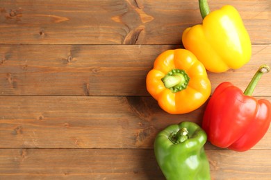 Photo of Ripe colorful bell peppers on wooden table, flat lay. Space for text