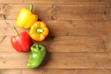 Photo of Ripe colorful bell peppers on wooden table, flat lay. Space for text