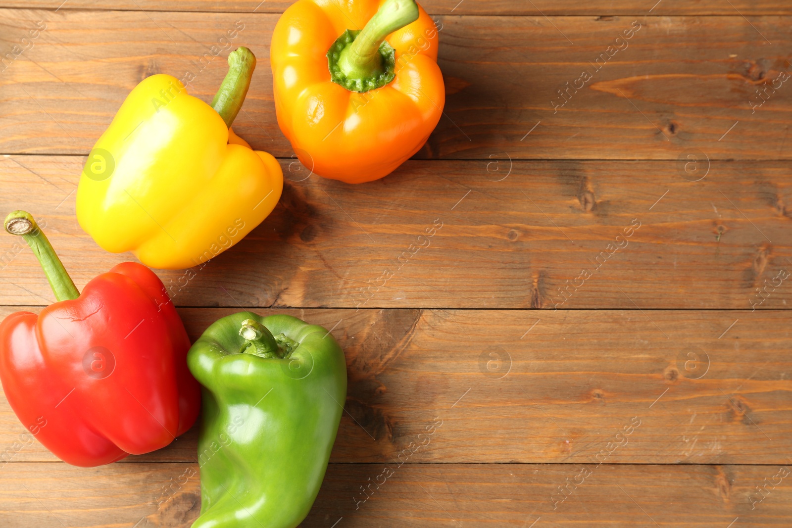 Ripe colorful bell peppers on wooden table, flat lay. Space for text Photo of Ripe colorful bell peppers on wooden table, flat lay. Space for text