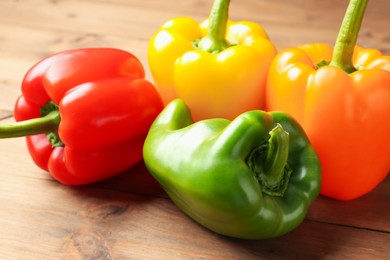 Photo of Ripe colorful bell peppers on wooden table, closeup