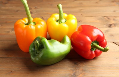 Photo of Ripe colorful bell peppers on wooden table, closeup