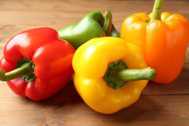 Photo of Ripe colorful bell peppers on wooden table, closeup