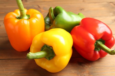 Photo of Ripe colorful bell peppers on wooden table, closeup