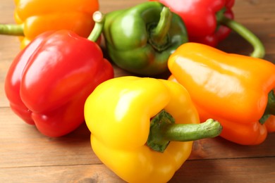 Photo of Ripe colorful bell peppers on wooden table, closeup
