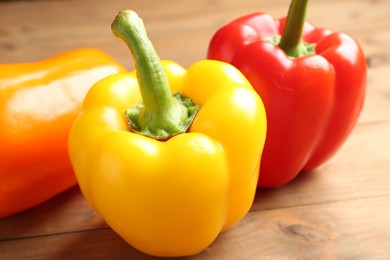 Photo of Ripe colorful bell peppers on wooden table, closeup