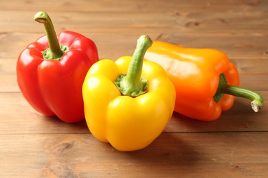 Photo of Ripe colorful bell peppers on wooden table, closeup