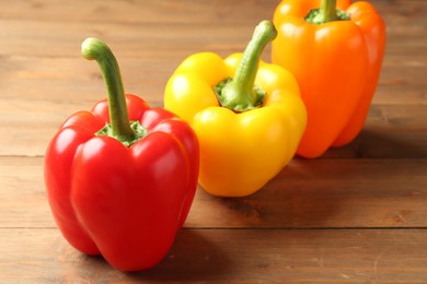 Photo of Ripe colorful bell peppers on wooden table, closeup