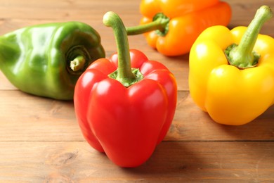 Photo of Ripe colorful bell peppers on wooden table, closeup