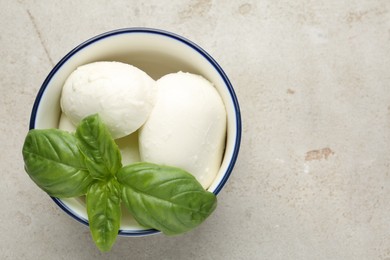 Photo of Tasty mozzarella cheese and basil on light table, top view. Space for text