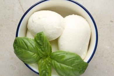 Photo of Tasty mozzarella cheese and basil on light table, top view