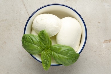 Photo of Tasty mozzarella cheese and basil on light table, top view