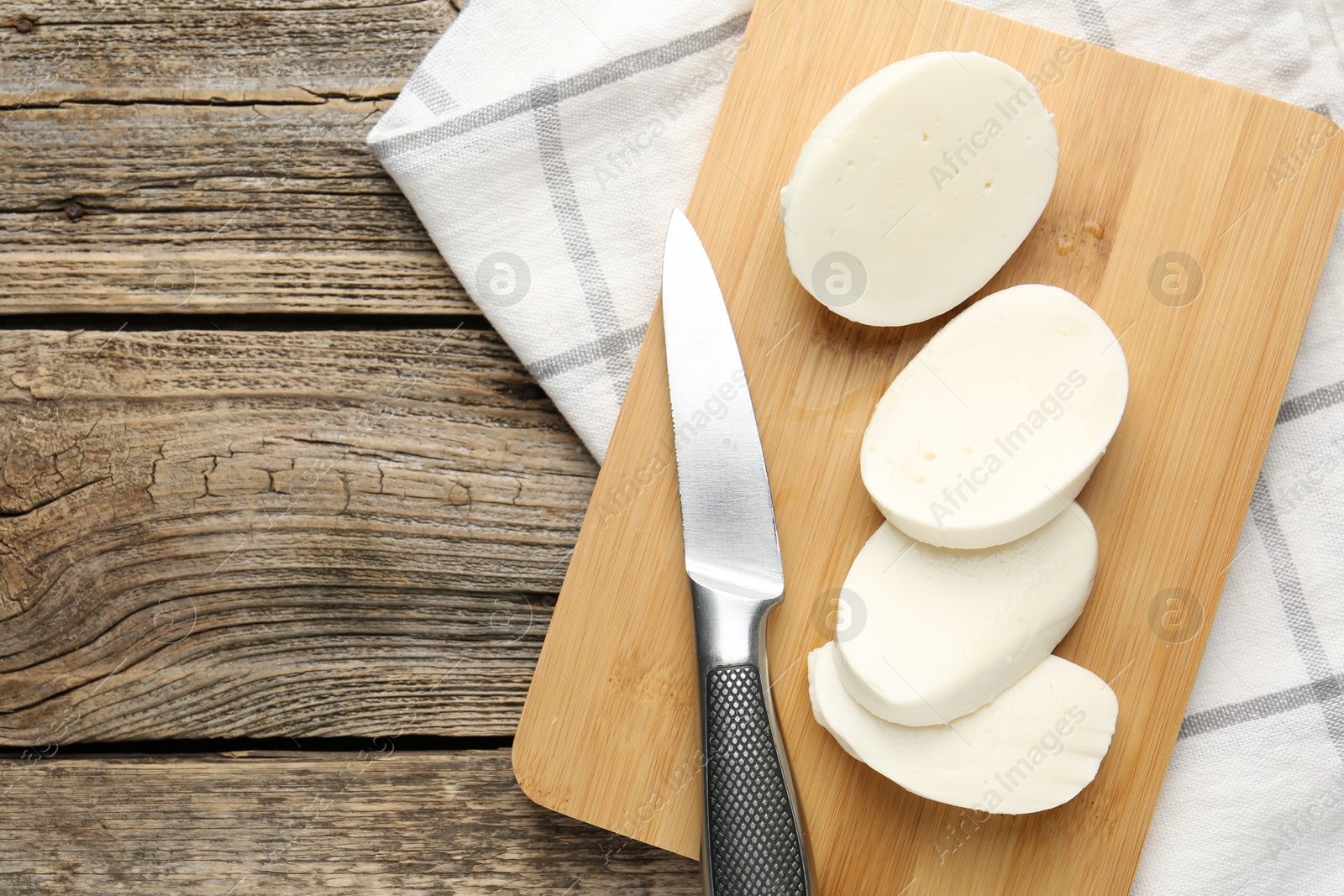 Cut mozzarella cheese and knife on wooden table, top view. Space for text Photo of Cut mozzarella cheese and knife on wooden table, top view. Space for text