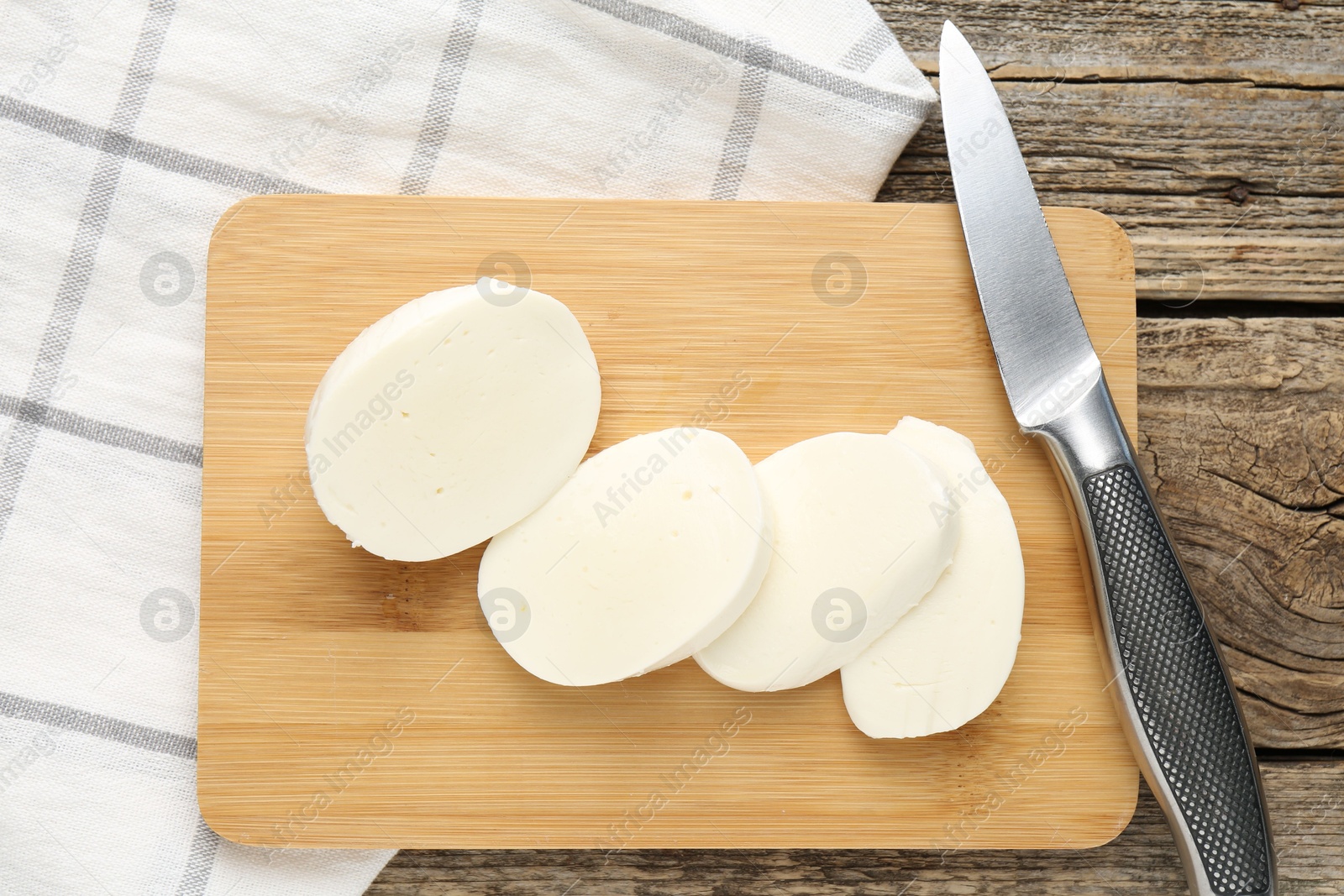 Cut mozzarella cheese and knife on wooden table, top view Photo of Cut mozzarella cheese and knife on wooden table, top view