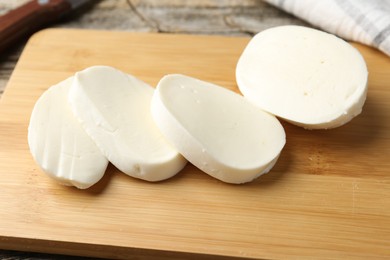 Photo of Cut mozzarella cheese on wooden table, closeup