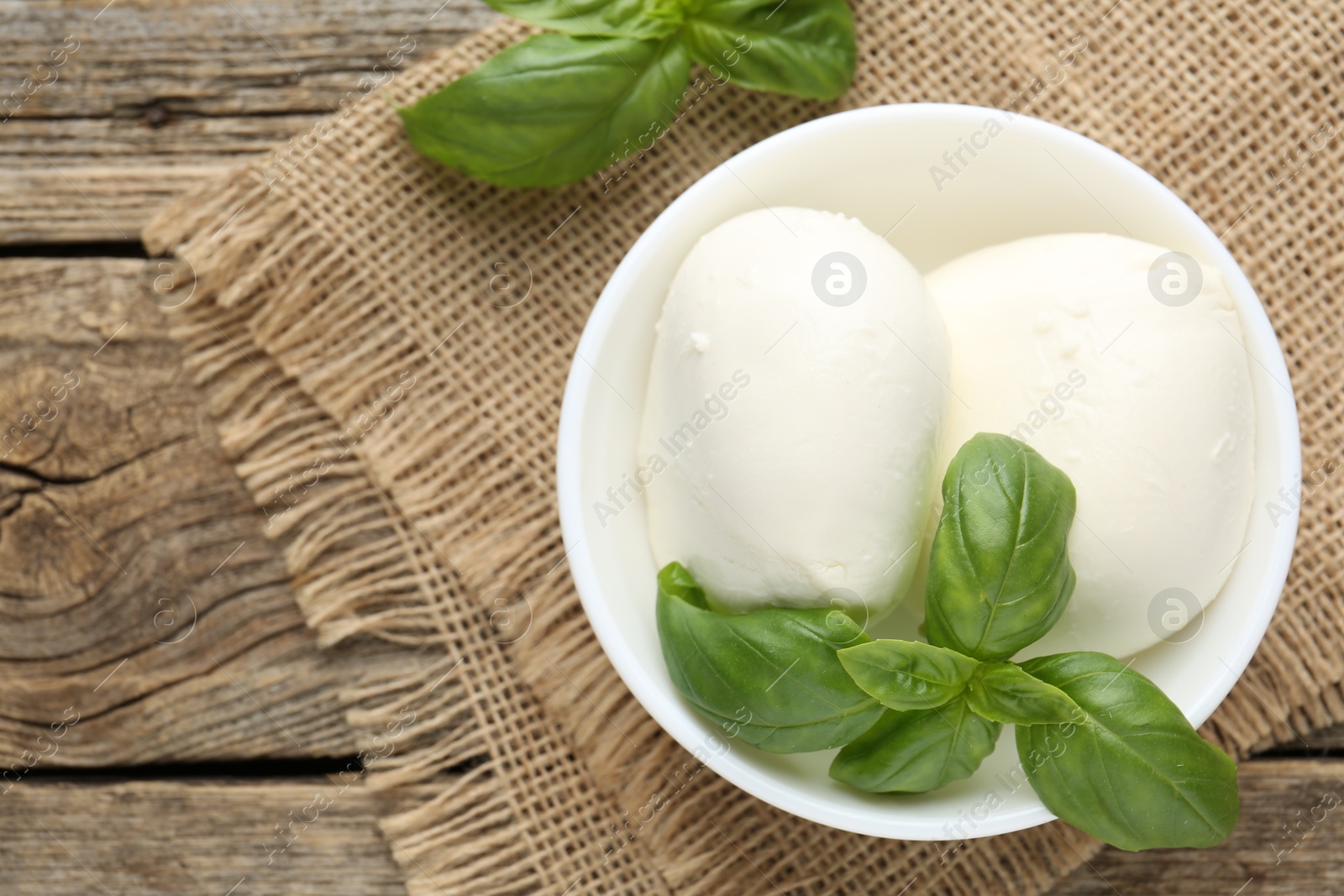 Tasty mozzarella cheese and basil on wooden table, top view Photo of Tasty mozzarella cheese and basil on wooden table, top view