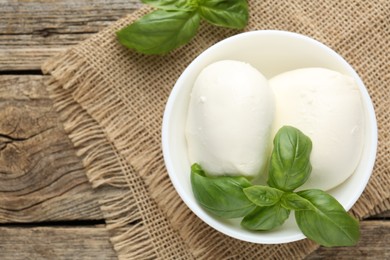 Photo of Tasty mozzarella cheese and basil on wooden table, top view