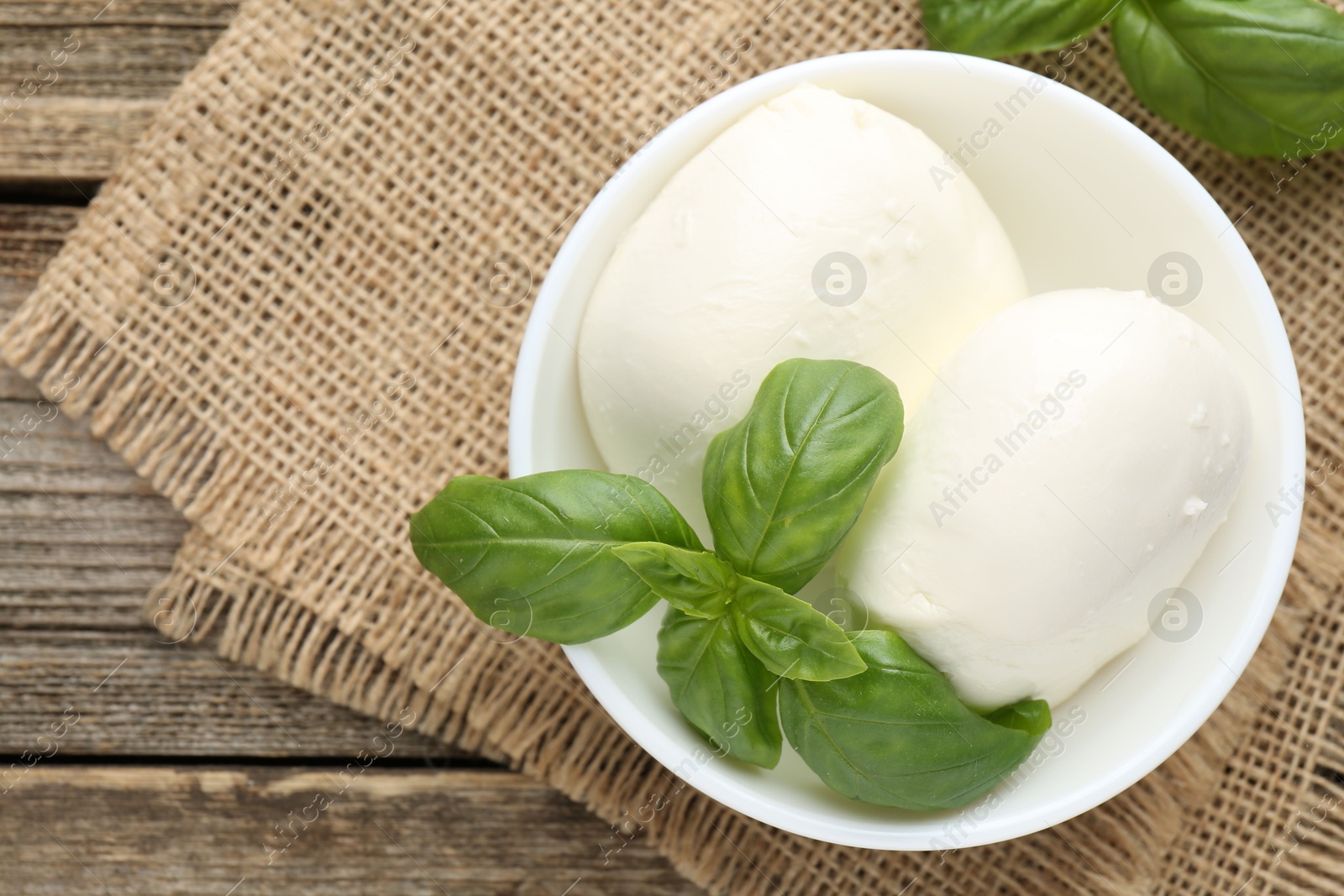 Tasty mozzarella cheese and basil on wooden table, top view Photo of Tasty mozzarella cheese and basil on wooden table, top view