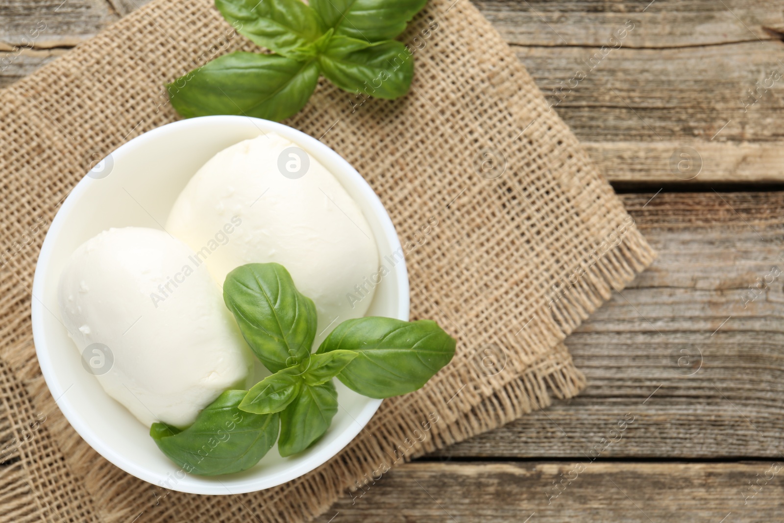 Tasty mozzarella cheese and basil on wooden table, top view. Space for text Photo of Tasty mozzarella cheese and basil on wooden table, top view. Space for text