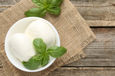 Photo of Tasty mozzarella cheese and basil on wooden table, top view. Space for text