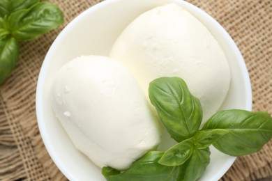 Photo of Tasty mozzarella cheese and basil on wooden table, top view