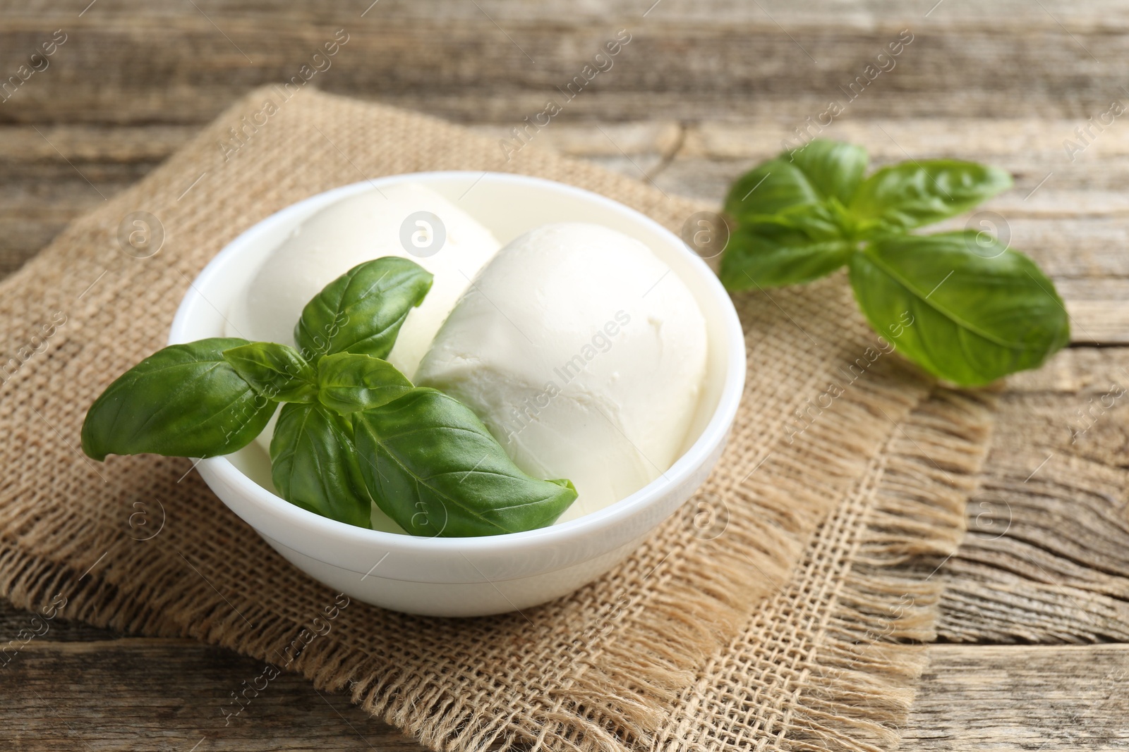 Tasty mozzarella cheese and basil on wooden table, closeup Photo of Tasty mozzarella cheese and basil on wooden table, closeup