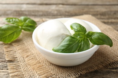 Photo of Tasty mozzarella cheese and basil on wooden table, closeup