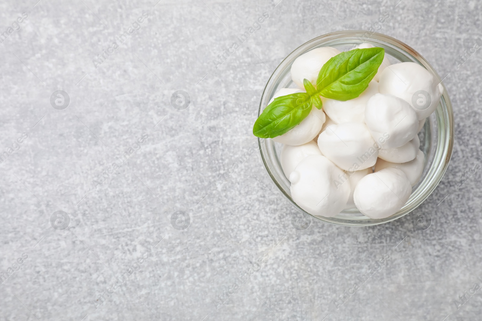 Mozzarella cheese balls and basil on light grey table, top view. Space for text Photo of Mozzarella cheese balls and basil on light grey table, top view. Space for text