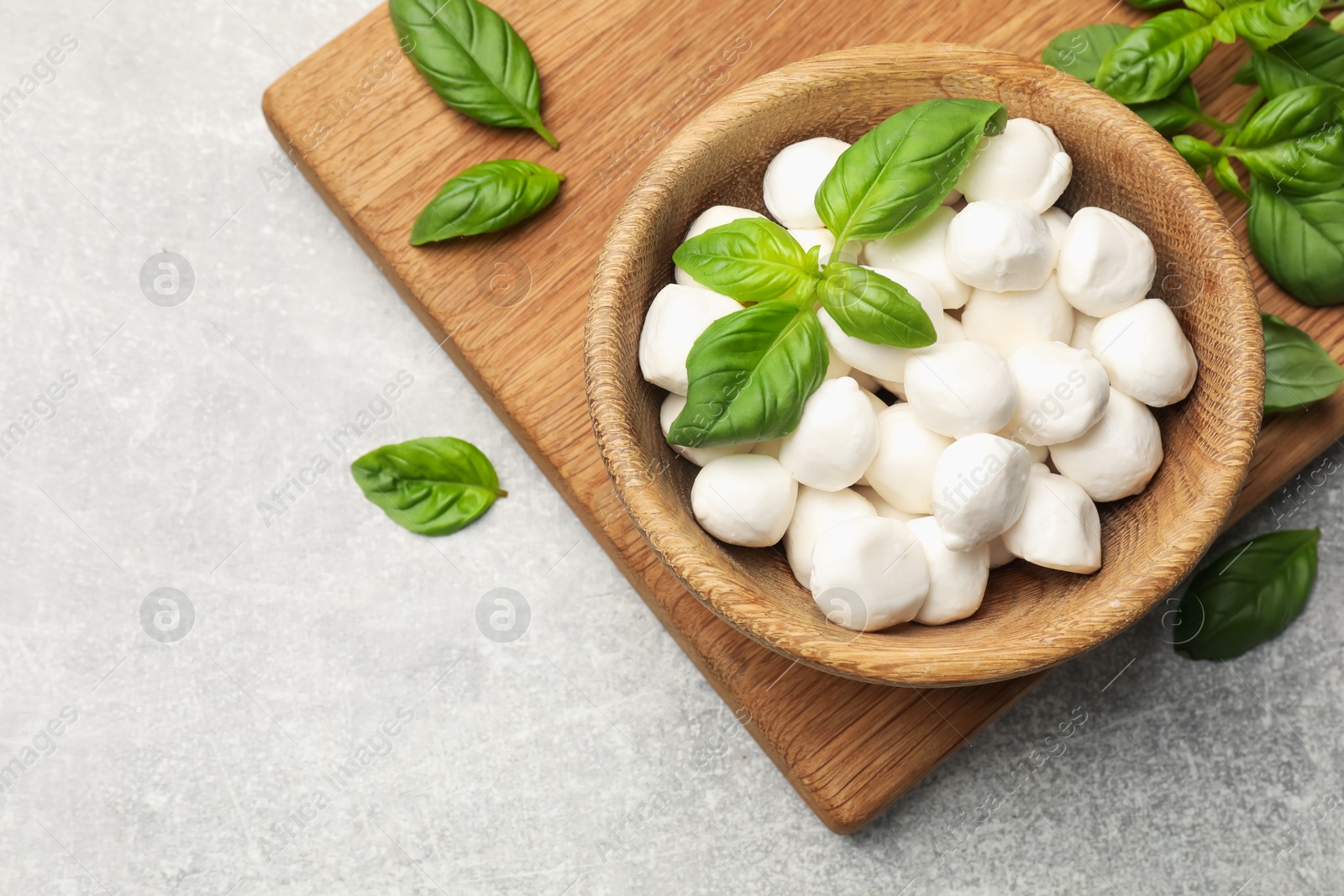 Mozzarella cheese balls and basil on light grey table, flat lay. Space for text Photo of Mozzarella cheese balls and basil on light grey table, flat lay. Space for text