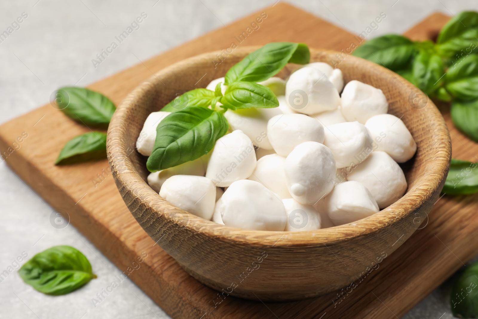 Mozzarella cheese balls and basil on light grey table, closeup Photo of Mozzarella cheese balls and basil on light grey table, closeup